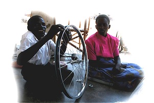 Disabled Man (Yasin - Left) shows girl how to repair a bicycle tire.